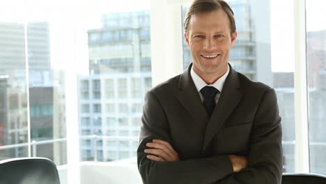 Smiling-businessman-standing-by-window