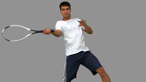 Man-training-while-playing-tennis-on-grey-screen
