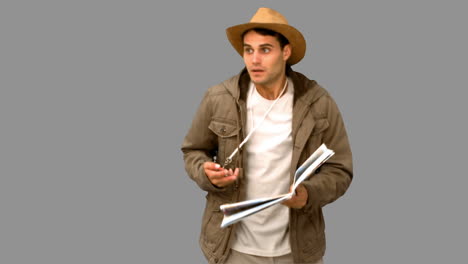 Man-with-a-map-and-a-compass-orienteering-on-grey-screen