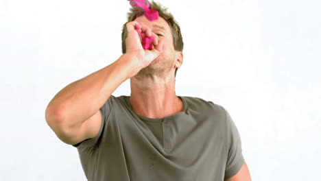 Man-blowing-pink-confetti-on-white-background