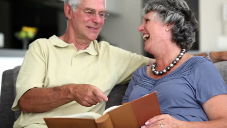 Mature-couple-laughing-while-looking-at-a-book-
