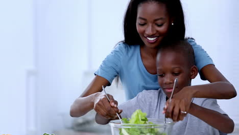 Mother-teaching-to-her-son-how-to-mix-salad
