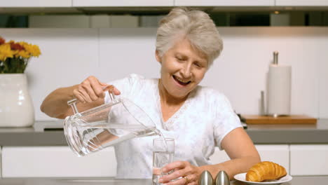 Elderly-woman-pouring-a-glass-of-water-for-breakfast