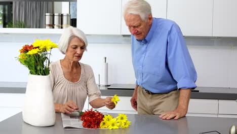 Woman-arranging-flowers-and-holds-one-to-husbands-nose