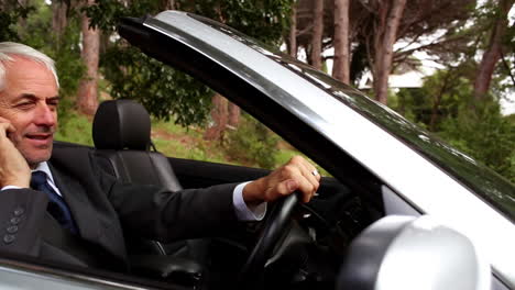 Happy-businessman-phoning-in-his-convertible-car-