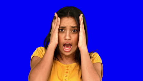 Shocked-woman-putting-hands-on-head-on-blue-screen