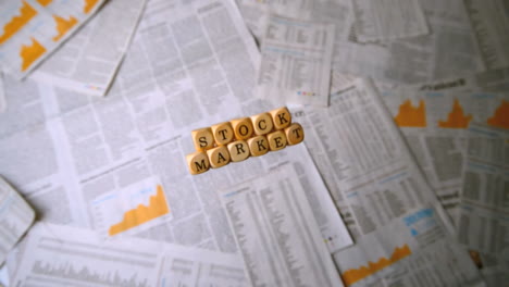 Wooden-dice-spelling-out-stock-market-falling-over-sheets-of-paper
