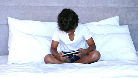 Little-boy-sitting-on-bed-