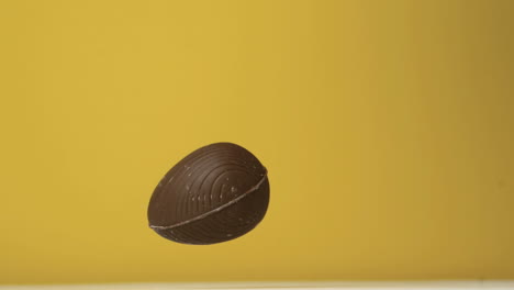 Chocolate-easter-egg-falling-against-yellow-background