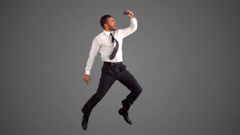 Businessman-jumping-and-taking-self-portrait-on-grey-background