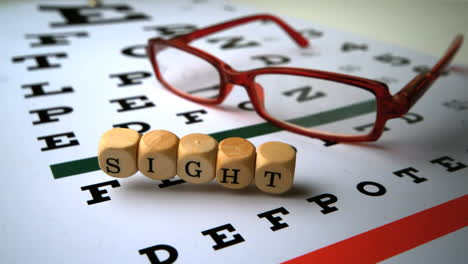 Dice-spelling-out-sight-falling-onto-eye-test-next-to-glasses