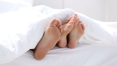 Pair-of-feet-playing-footsie-under-the-covers