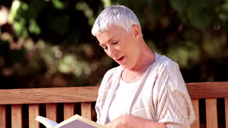 Mature-woman-reading-a-book-on-a-bench