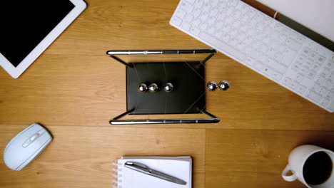 Overhead-of-newtons-cradle-toy-on-office-desk