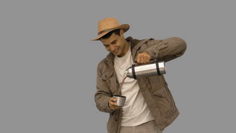 Man-pouring-coffee-from-a-vacuum-flask-on-grey-screen