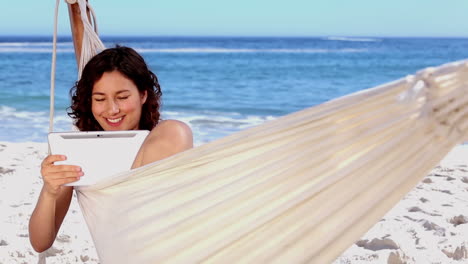 Smiling-woman-using-tablet-in-a-hammock