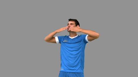 Football-player-waving-a-kissing-at-people-on-grey-screen