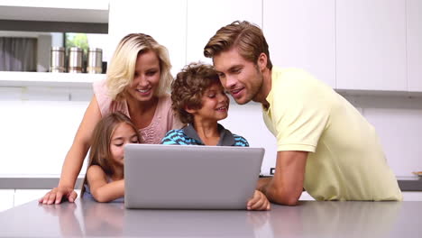 Family-looking-at-laptop-in-kitchen