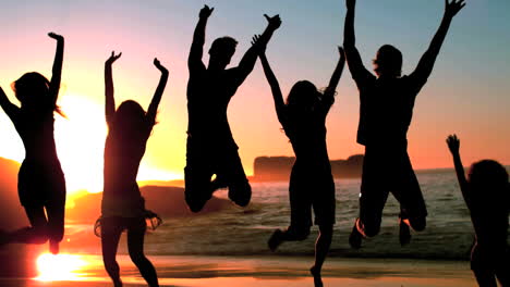 Group-of-friends-jumping-on-the-beach-under-the-dusk