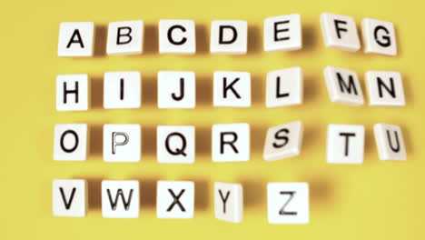 Plastic-letters-bouncing-and-showing-alphabet-on-yellow-surface