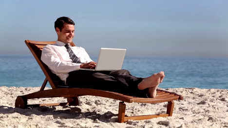 Un-Hombre-De-Negocios-Sin-Estrés-Usando-Una-Computadora-Portátil-En-La-Playa