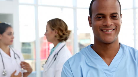 Nurse-smiling-and-standing-in-front-of-medical-team