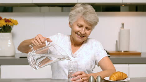 Retired-woman-pouring-a-glass-of-water-for-breakfast