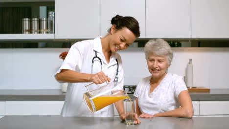 Enfermera-A-Domicilio-Sirviendo-Jugo-De-Naranja-Para-El-Paciente-En-La-Cocina