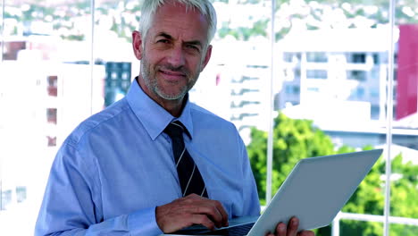 Businessman-using-his-tablet-and-smiling