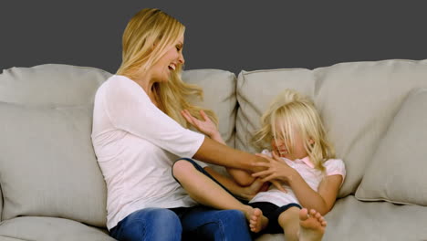 Mother-tickling-her-daughter-on-sofa