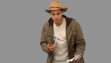 Man-orienteering-with-a-map-and-a-compass-on-grey-screen
