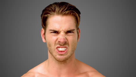 Young-man-showing-his-anger-on-grey-background