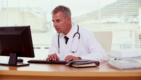 Smiling-doctor-using-his-computer-