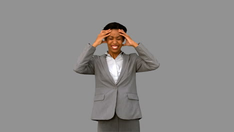 Furious-businesswoman-holding-her-head-on-grey-screen
