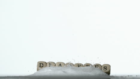 White-dice-spelling-out-diabetes-falling-over-pile-of-sugar-on-white-background