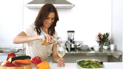 Smiling-woman-pouring-white-wine-in-her-glass