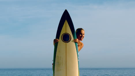 Female-surfer-peeking-out-from-behind-her-board