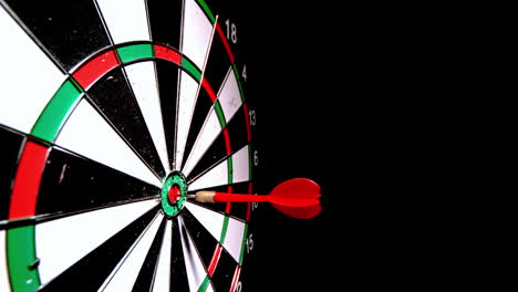 Red-dart-hitting-the-bulls-eye-on-black-background