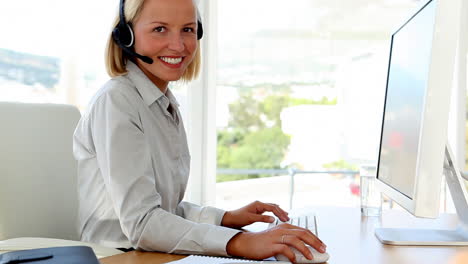 Businesswoman-talking-on-headset-and-typing