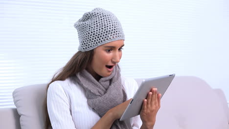 Brunette-sitting-on-sofa-using-her-tablet-pc