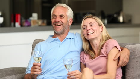 Couple-watching-tv-while-holding-white-wine-glass