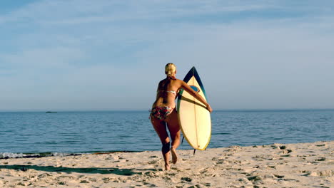 Blonde-surfer-picking-up-board-and-running-towards-ocean