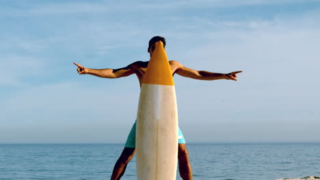 Attractive-man-hiding-behind-his-surfboard