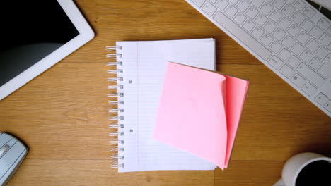 Pink-post-its-falling-on-notepad-on-office-desk