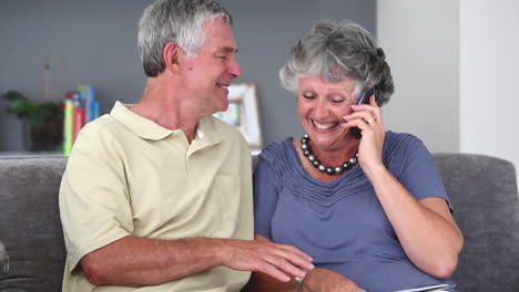 Älteres-Paar,-Das-Ein-Telefongespräch-Führt-Und-Dabei-Ein-Buch-Liest