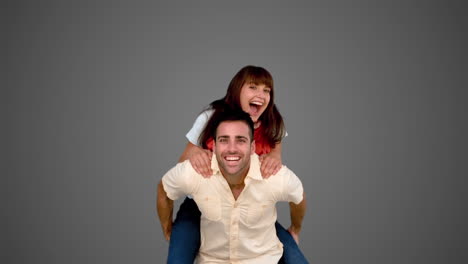 Smiling-man-giving-to-his-friend-a-piggyback-on-grey-background