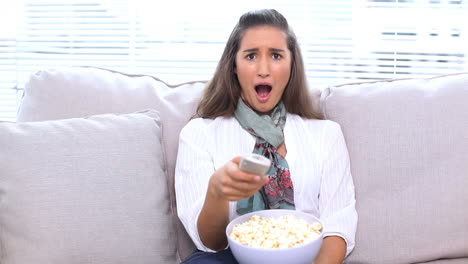Brunette-watching-television-and-eating-popcorn-
