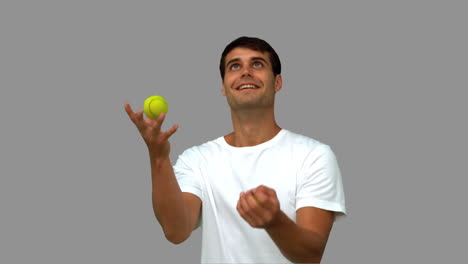 Man-dribbling-with-tennis-balls-on-grey-screen