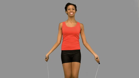 Cheerful-woman-working-out-with-a-rope-on-grey-screen