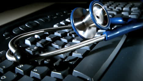 Blue-stethoscope-falling-and-bouncing-onto-computer-keyboard-